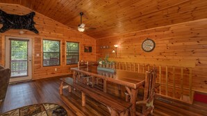 A wooden cabin interior with a dining table, benches, a ceiling fan, and a clock on the wall. - Private Cabin with Game Room (SEVIERVILLE)