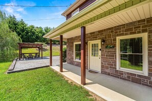A brick house with a covered porch, a small garden, and a gazebo. - Heaven Sent - Tastefully Decorated Cabin with Fireplace (PIGEON FORGE)