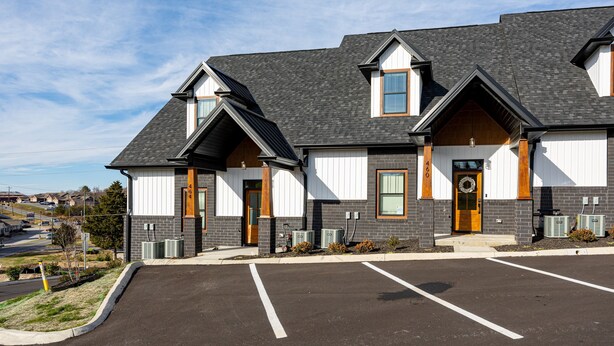 A two-story building with a dark roof, white and gray exterior walls, and a front entrance with a wooden door. - The Wooden Sanctuary (SEVIERVILLE)