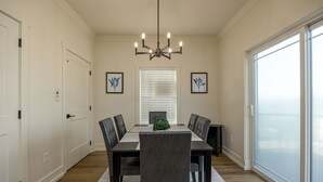A dining room with a table set for six, a chandelier, and a view through a large window. - The Wooden Sanctuary (SEVIERVILLE)