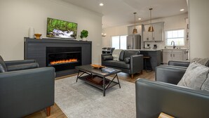 A modern living room with a fireplace, grey sofas, and a flat-screen TV. - The Wooden Sanctuary (SEVIERVILLE)