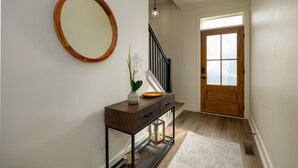 A hallway with a wooden console table, a mirror, a vase with flowers, and a door with frosted glass panels. - The Wooden Sanctuary (SEVIERVILLE)