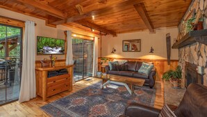 Una sala de estar acogedora con chimenea, techo de madera y un televisor grande.