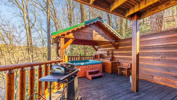 Una terraza de madera con jacuzzi, una parrilla y un pérgola de madera.