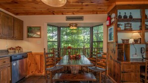 Una cocina rústica con armarios de madera, una amplia mesa de comedor y una ventana con vistas a la vegetación.