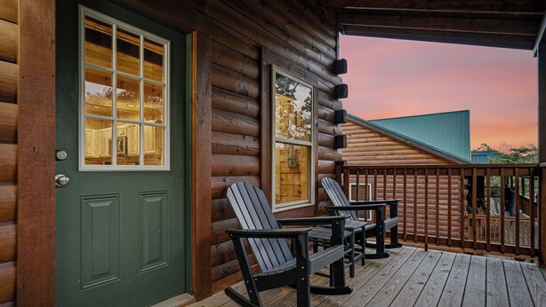 Une cabane en rondins avec une véranda, des fauteuils à bascule et une vue sur l’intérieur.