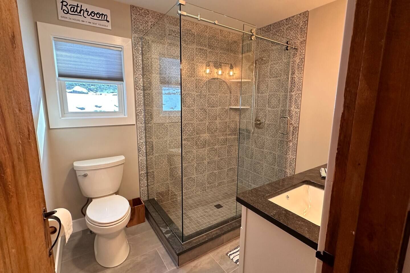 A bathroom with a glass-enclosed shower, a toilet, and a sink.