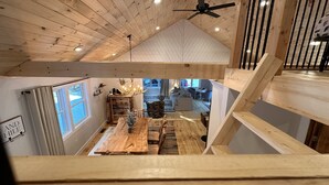 A wooden interior with a dining area, a staircase, and a view of the living room.
