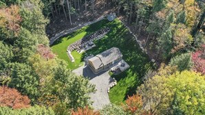 An aerial view of a lodge surrounded by dense forest, with a stone pathway leading to the main building.