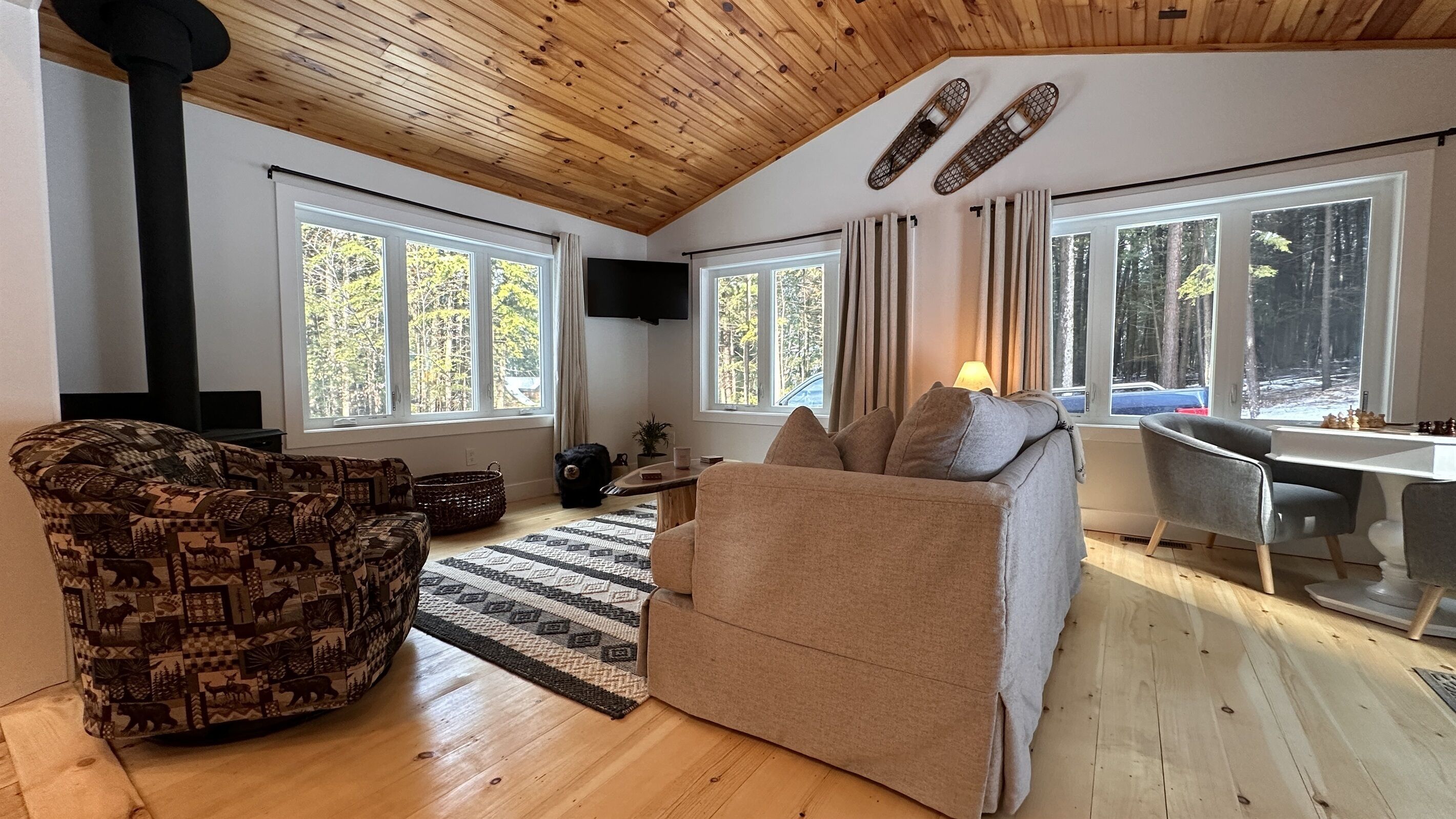 Ein gemütliches Wohnzimmer mit Kamin, einer Couch, einem gemusterten Sessel und einem Schreibtisch mit Stuhl.