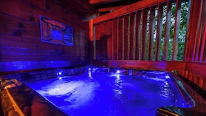 Una cabaña de madera con un jacuzzi iluminado con luces azules.