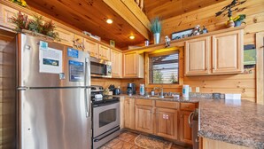 A kitchen with wooden cabinets, stainless steel appliances, and a granite countertop. - Galloping In The Mountains (PIGEON FORGE)