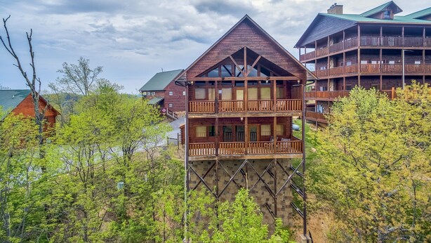 Un edificio in legno a più piani con balconi, circondato da alberi e da uno specchio d'acqua.