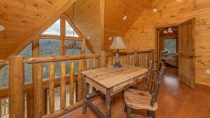 A wooden interior with a dining table and chairs, a chandelier, and a view of the outdoors. - Retreat To The Mountain Lair (SEVIERVILLE)