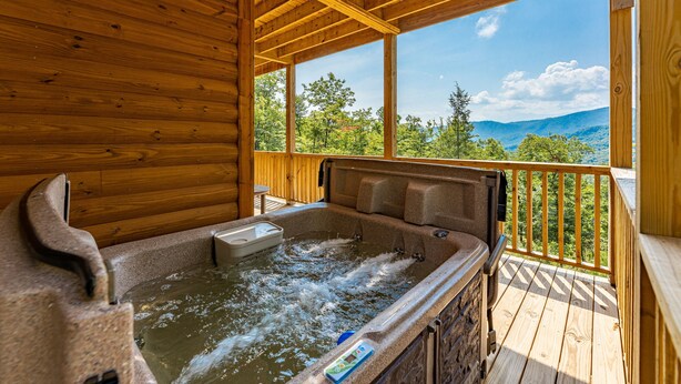 A wooden cabin with a hot tub and a wooden deck overlooking a mountainous landscape. - Retreat To The Mountain Lair (SEVIERVILLE)
