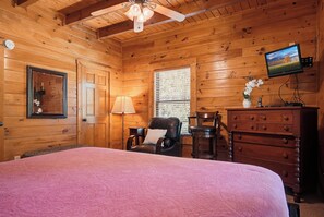 A wooden room with a bed, a chair, a dresser, a television, and a window with blinds. - Crown Your Vacation With Fun Nearby (SEVIERVILLE)