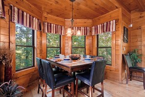 A wooden cabin interior with a dining table, chairs, and a hanging light fixture. - Crown Your Vacation With Fun Nearby (SEVIERVILLE)