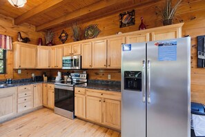 A kitchen with wooden cabinets, stainless steel appliances, and a refrigerator with a water dispenser. - Crown Your Vacation With Fun Nearby (SEVIERVILLE)