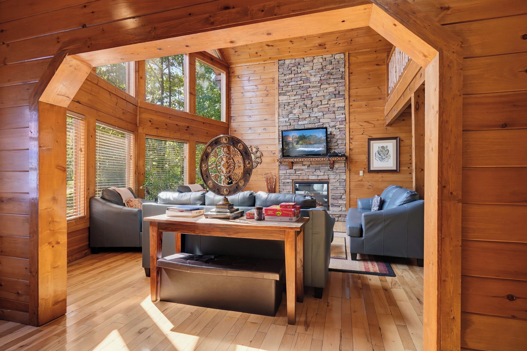 L’intérieur d’un chalet accueillant, avec une cheminée en pierre, un téléviseur fixé au-dessus et un grand miroir décoratif.