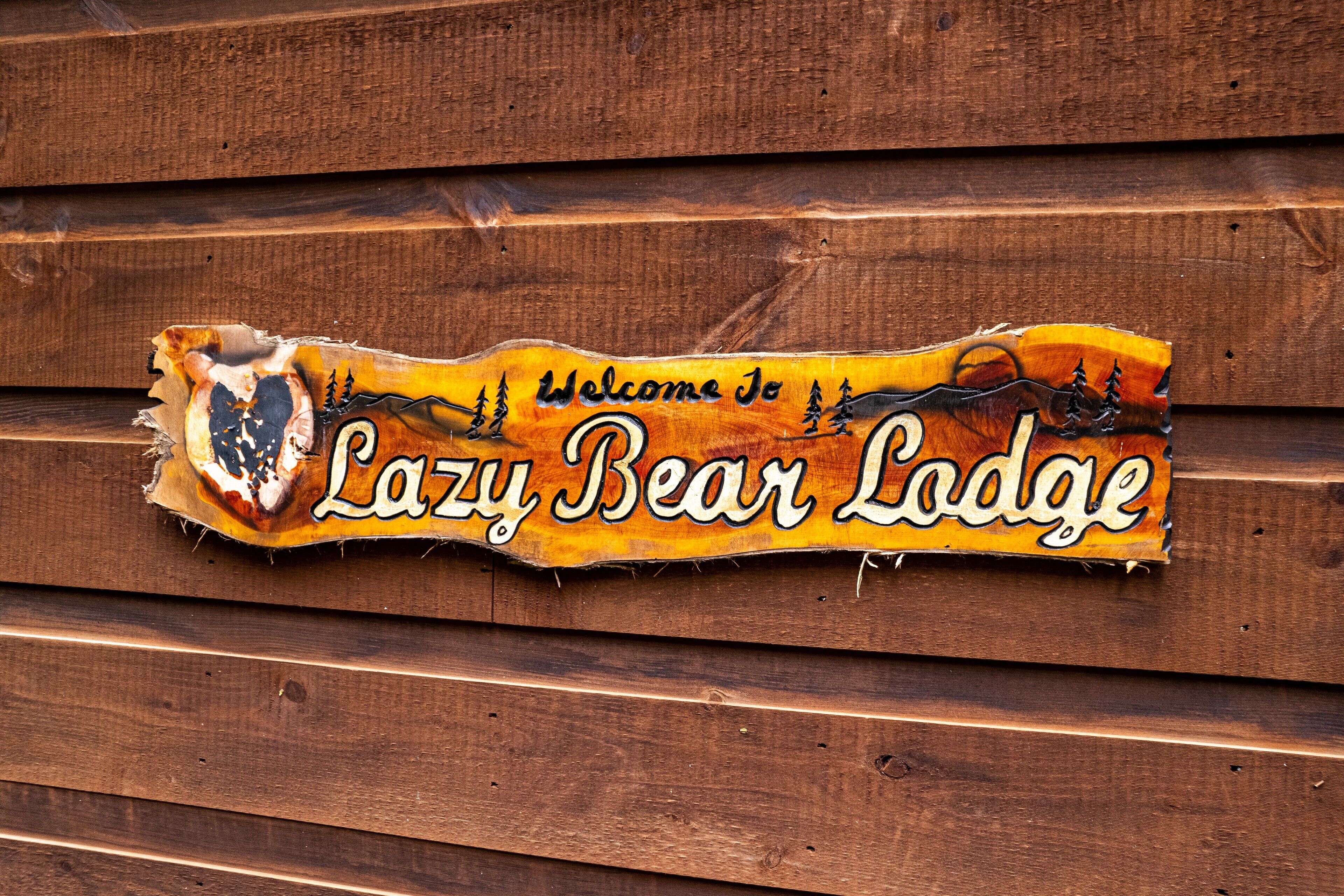 A wooden sign with the text "Welcome to Lazy Bear Lodge" and a bear illustration.