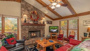A cozy living room with a stone fireplace, leather sofas, and a television. - Pigeon Forge*Easy Access Rds*WiFi*Hot Tub (SEVIERVILLE)