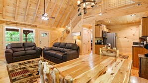 A spacious wooden interior with a dining table, two leather sofas, and a kitchen area. - Close to Pigeon Forge*Keurig*Hot Tub (PIGEON FORGE)