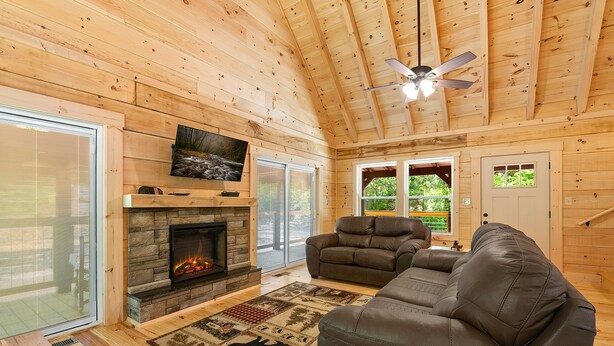 A cozy cabin interior with a stone fireplace, leather sofa, and a ceiling fan. - Close to Pigeon Forge*Keurig*Hot Tub (PIGEON FORGE)