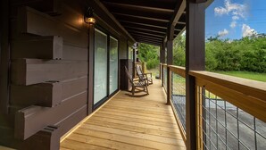 A wooden deck with a rocking chair, a railing, and a view of greenery. - Close to Pigeon Forge*Keurig*Hot Tub (PIGEON FORGE)