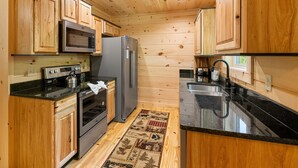 A compact kitchen with wooden cabinets, a stainless steel refrigerator, a microwave, and a stove. - Close to Pigeon Forge*Keurig*Hot Tub (PIGEON FORGE)