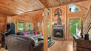 Ein gemütliches Blockhaus mit Kamin, Holzwänden und einer Couch.
