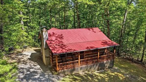 A cabin with a red roof, wooden deck, and a gravel path leading to it. - Secluded*Enclosed Hot Tub*Cozy (PIGEON FORGE)