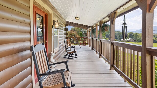 A wooden porch with a railing, a rocking chair, and a bench.