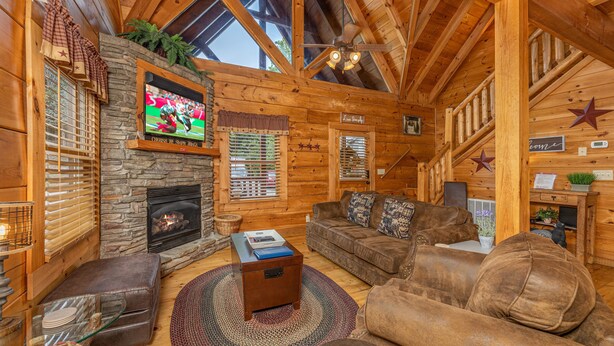 A cozy log cabin interior with a stone fireplace, wooden ceiling beams, and a comfortable seating area. - Simplicity Like It Should Be: In A Cabin (PIGEON FORGE)
