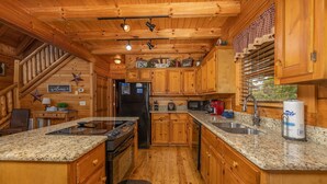 A wooden cabin-style kitchen with granite countertops, a built-in stove, and a refrigerator. - Simplicity Like It Should Be: In A Cabin (PIGEON FORGE)