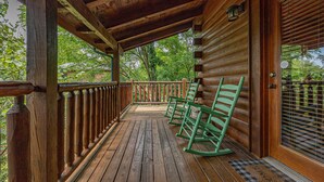 A wooden porch with a wooden railing, a door with a window, and two rocking chairs. - Unplug And Unwind In A Pigeon Forge Luxury Cabin (PIGEON FORGE)