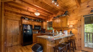 A wooden cabin kitchen with a refrigerator, microwave, and wooden cabinets. - Unplug And Unwind In A Pigeon Forge Luxury Cabin (PIGEON FORGE)
