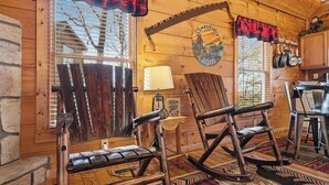 A rustic wooden interior with rocking chairs, a wooden table, and a sign reading 'Old Bear Lodge.' - Relax And Enjoy The Incredible View From Here (GATLINBURG)