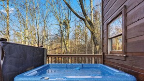 A wooden cabin with a hot tub, a window, and a view of leafless trees. - Relax And Enjoy The Incredible View From Here (GATLINBURG)