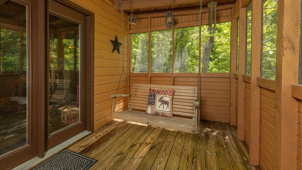 Un portico in legno con una panchina, ampie finestre e lanterne appese.