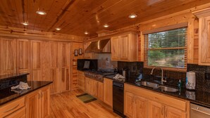 Cucina in stile baita in legno, con fornello, lavello e forno a incasso.