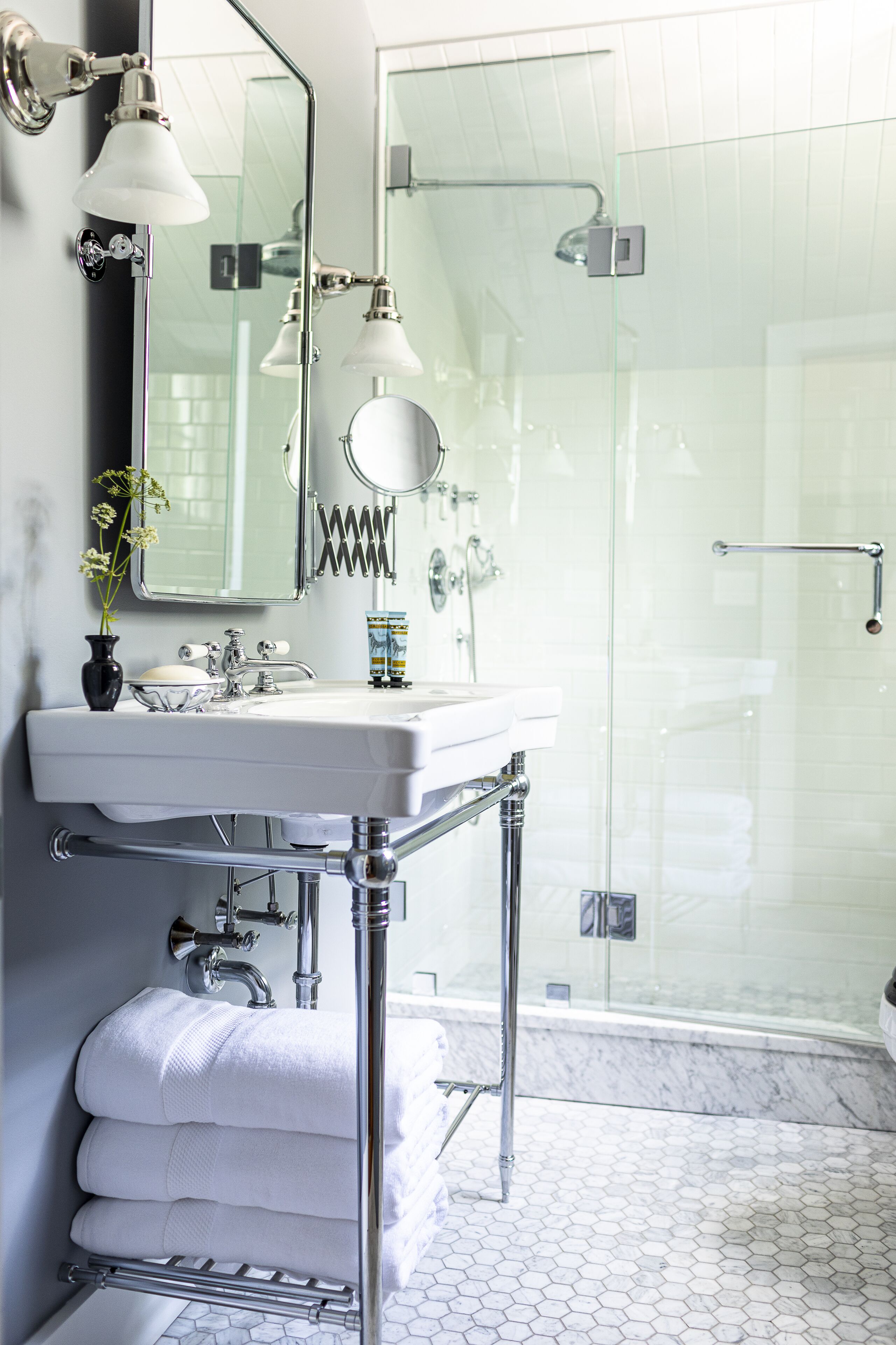 A modern bathroom with a white sink, mirror, and glass shower enclosure.