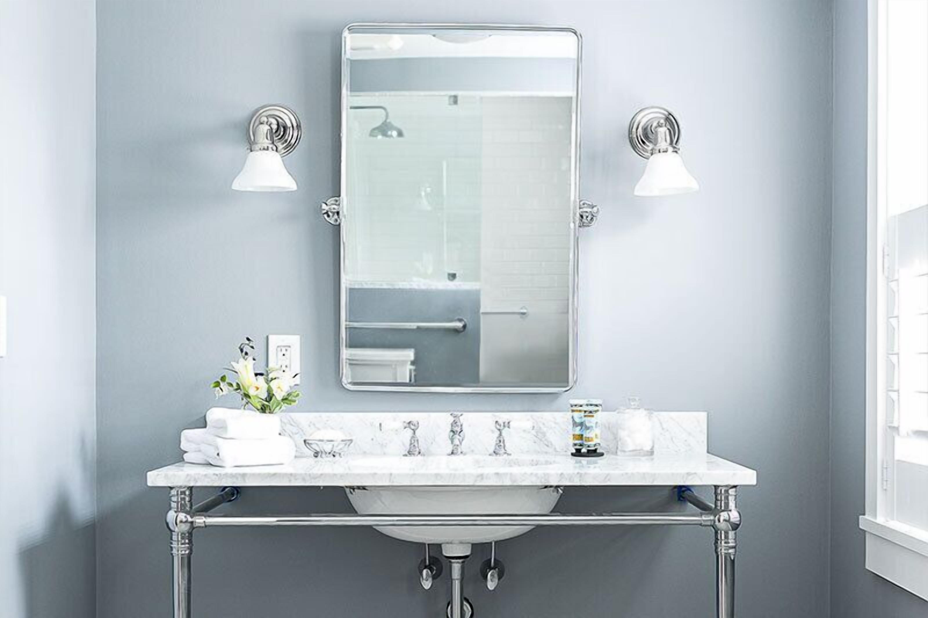 A modern bathroom with a marble sink, two wall-mounted lights, and a large mirror.