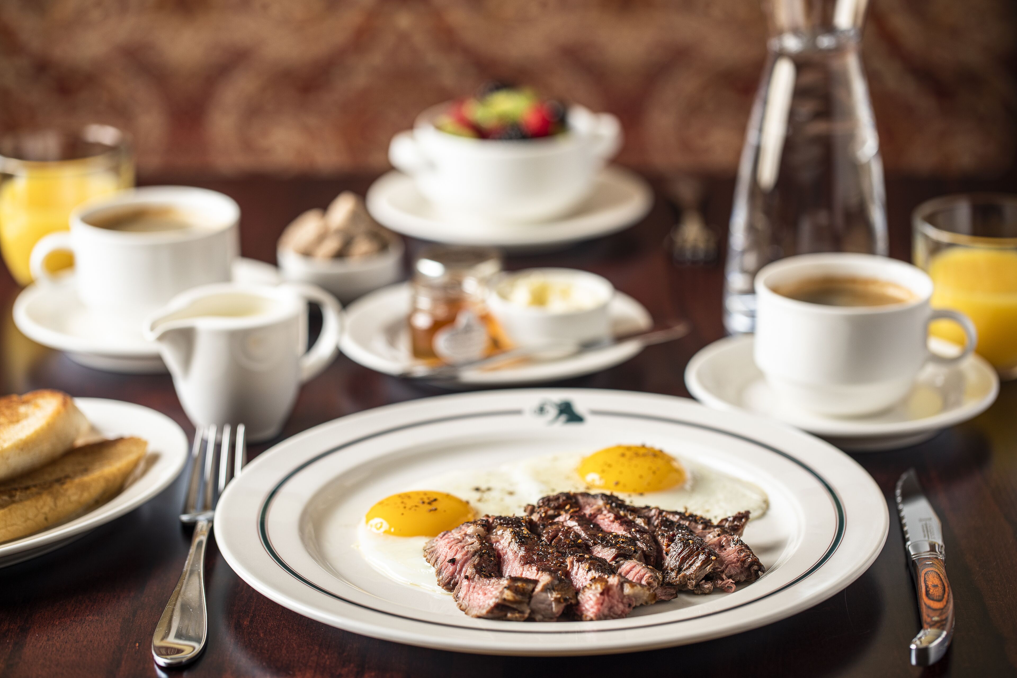 A breakfast setting with steak, eggs, toast, and coffee.