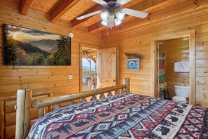 A wooden cabin bedroom with a bed, a ceiling fan, a mounted TV, and a door leading to an outdoor area. - Feel Like A Millionaire Relaxing In These Views (SEVIERVILLE)