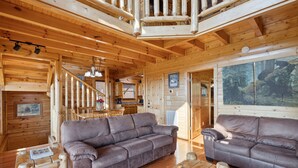 A wooden cabin interior with two sofas, a dining table, and a staircase. - Feel Like A Millionaire Relaxing In These Views (SEVIERVILLE)