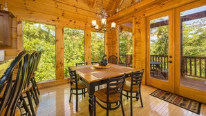 L’intérieur d’un chalet en bois, avec une table à manger, des chaises et un lustre.