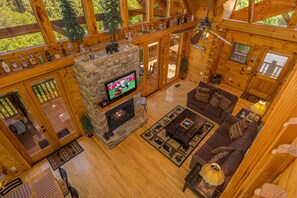 Interior acogedor de una cabaña de troncos con chimenea de piedra, muebles de madera y televisor.
