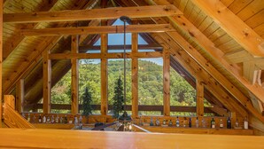 Un intérieur en bois avec un plafond incliné, de grandes fenêtres et un banc en bois sur lequel sont posées des bouteilles.