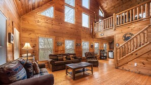 A spacious wooden cabin with a loft bedroom, a living room with a sofa and coffee table, and a staircase leading to the upper level. - Making Memories You'll Never Forget (SEVIERVILLE)