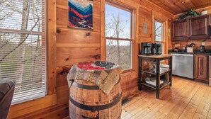 A wooden cabin interior with a kitchen area, a wooden barrel, and a poster on the wall. - Making Memories You'll Never Forget (SEVIERVILLE)